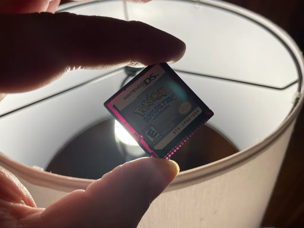 A Pokémon cartridge in front of a light bulb